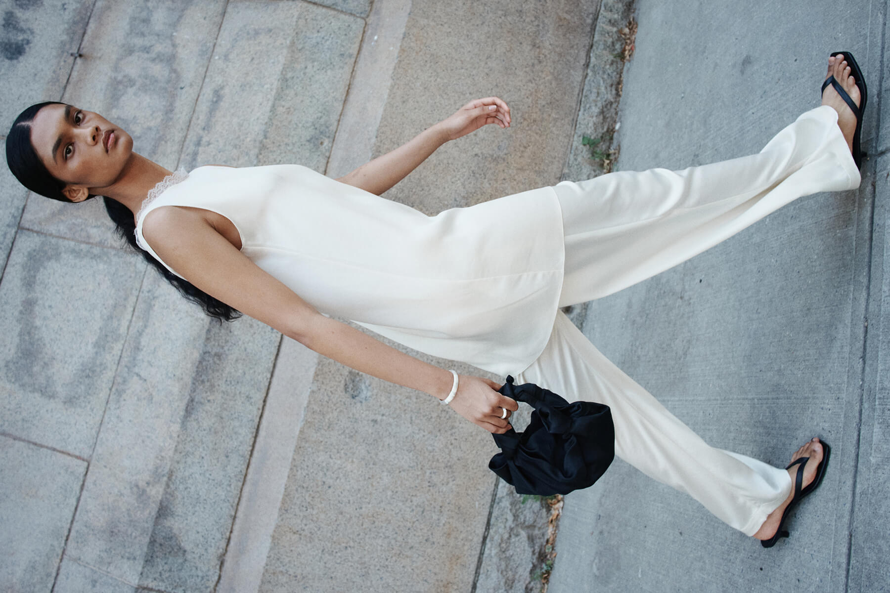 Woman walking in Barb creme colored dress layered over pants with sandals.