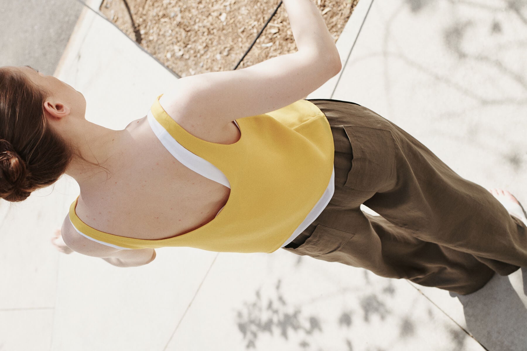 Back of woman wearing cypress Daniel linen pants with yellow tank.