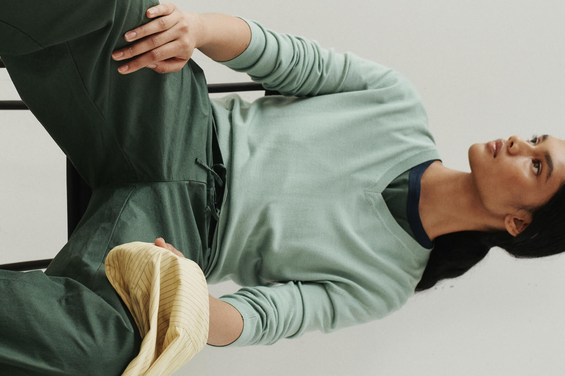Woman sitting down in green sweater and carpenter pant