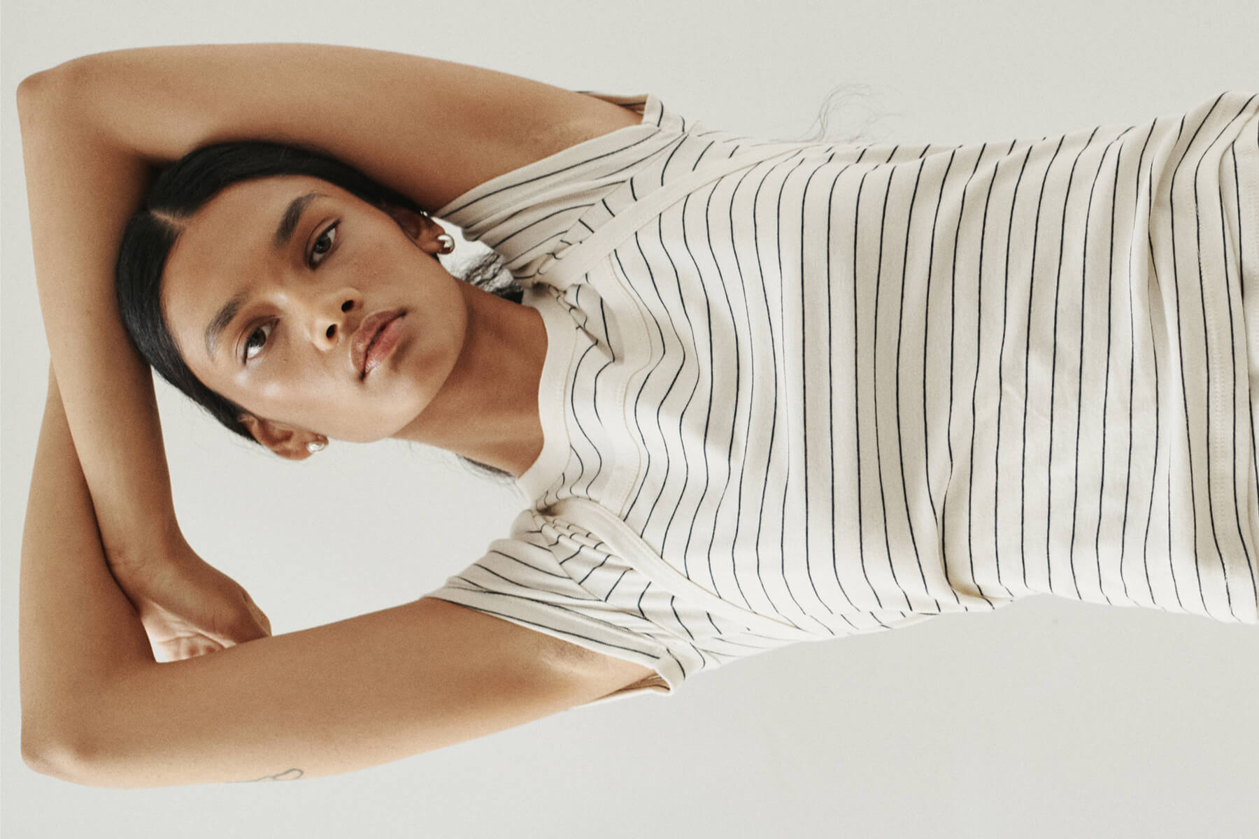 Close up of woman with arms above head in stripe layered tees.