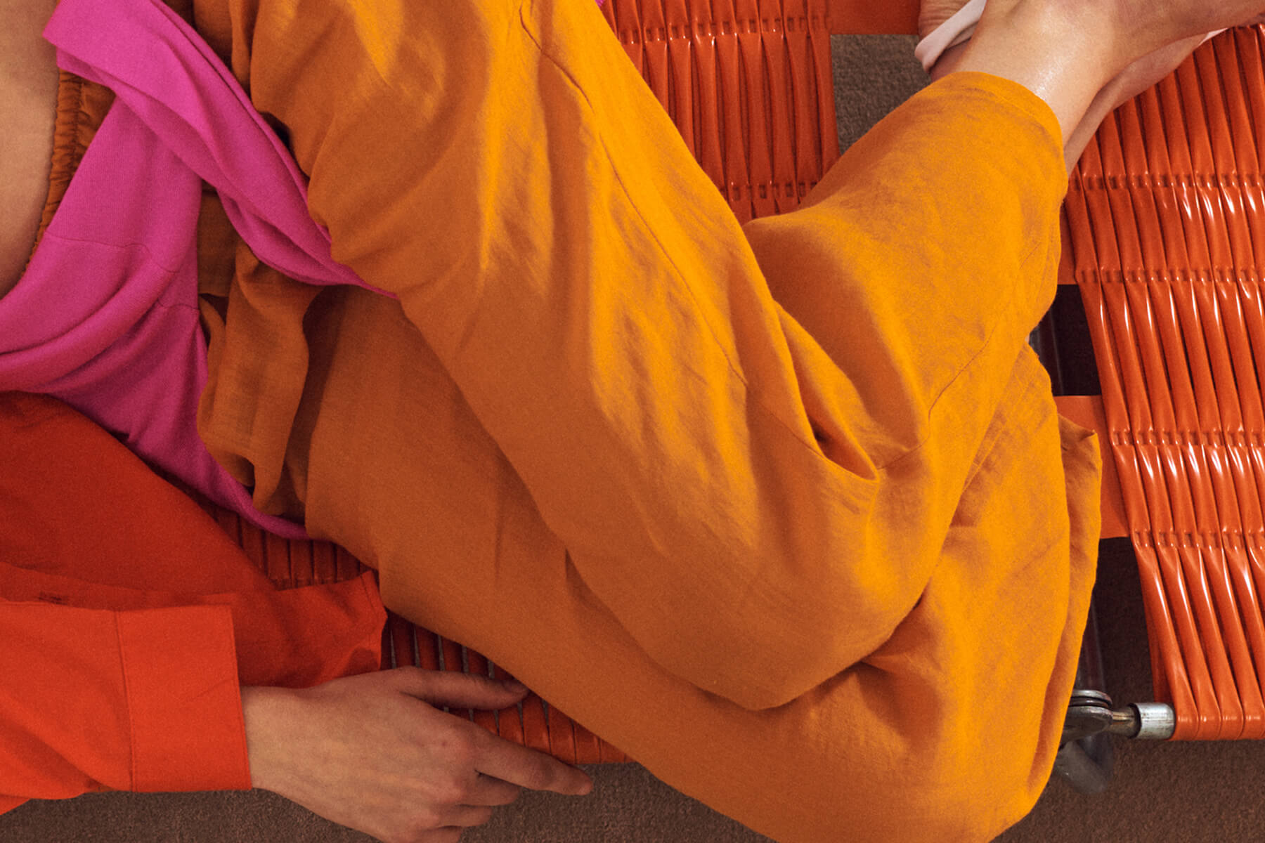Close up of Orange linen pants, with pink sweater draped over.