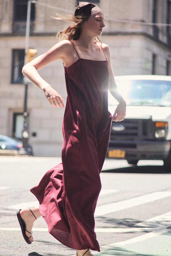 Woman in bordeaux maxi dress and sandals in street.