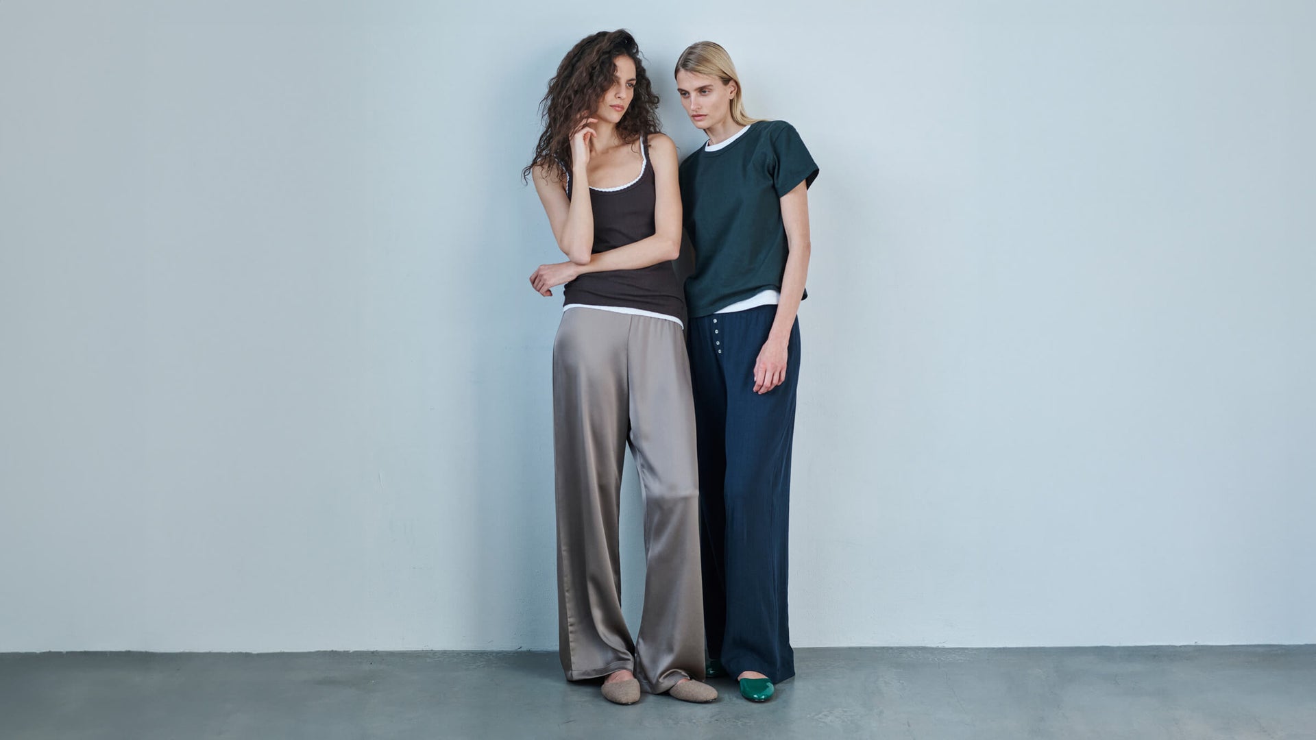 Two women standing against a wall in Pointelle tanks, Barb pant in taupe, and Margo tee forest layered over white with Pointelle boxer pants.