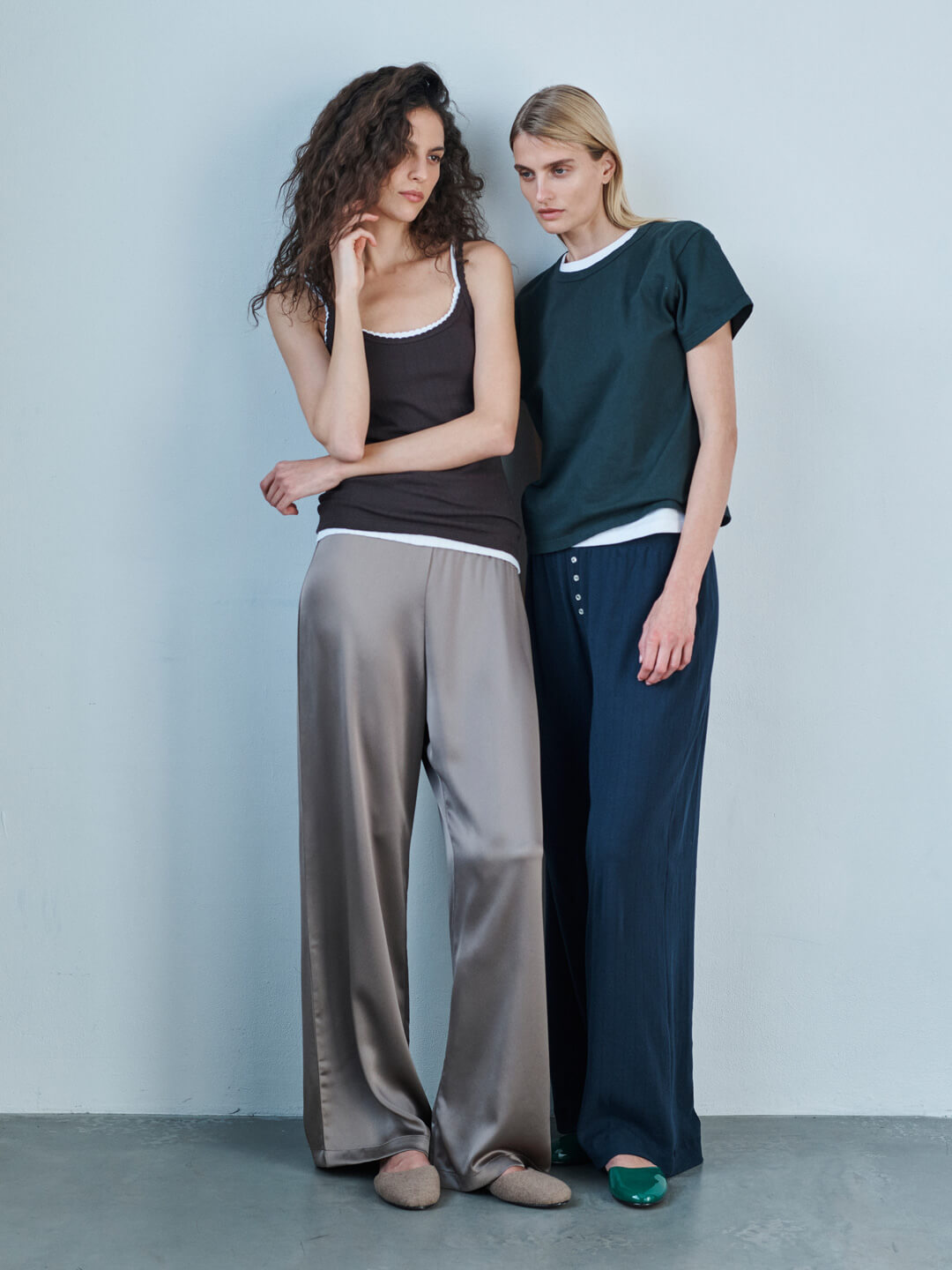 Two women standing against a wall in Pointelle tanks, Barb pant in taupe, and Margo tee forest layered over white with Pointelle boxer pants.