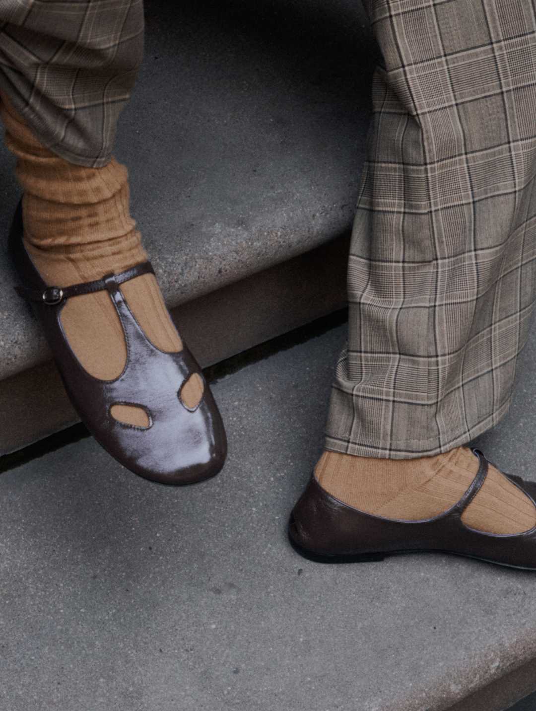 Close up of plaid pants and brown mary jane shoes on model on stairs.