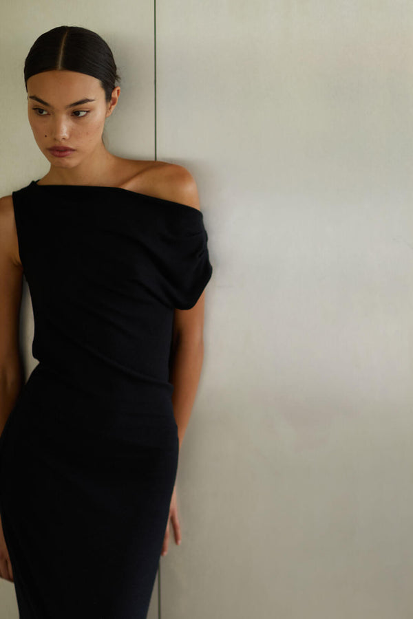 Woman leaning against wall in black Lauren ruched dress