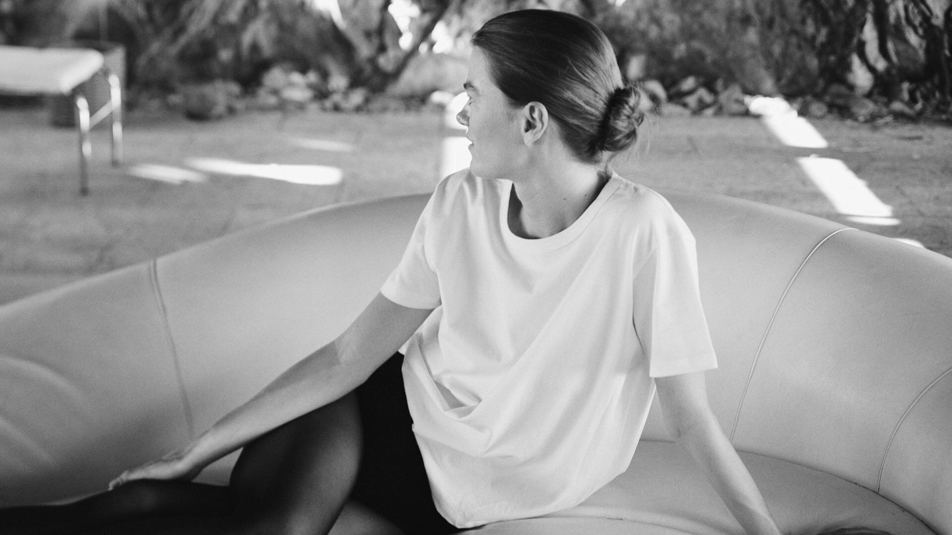 Woman in white t-shirt and tights sitting on couch outside