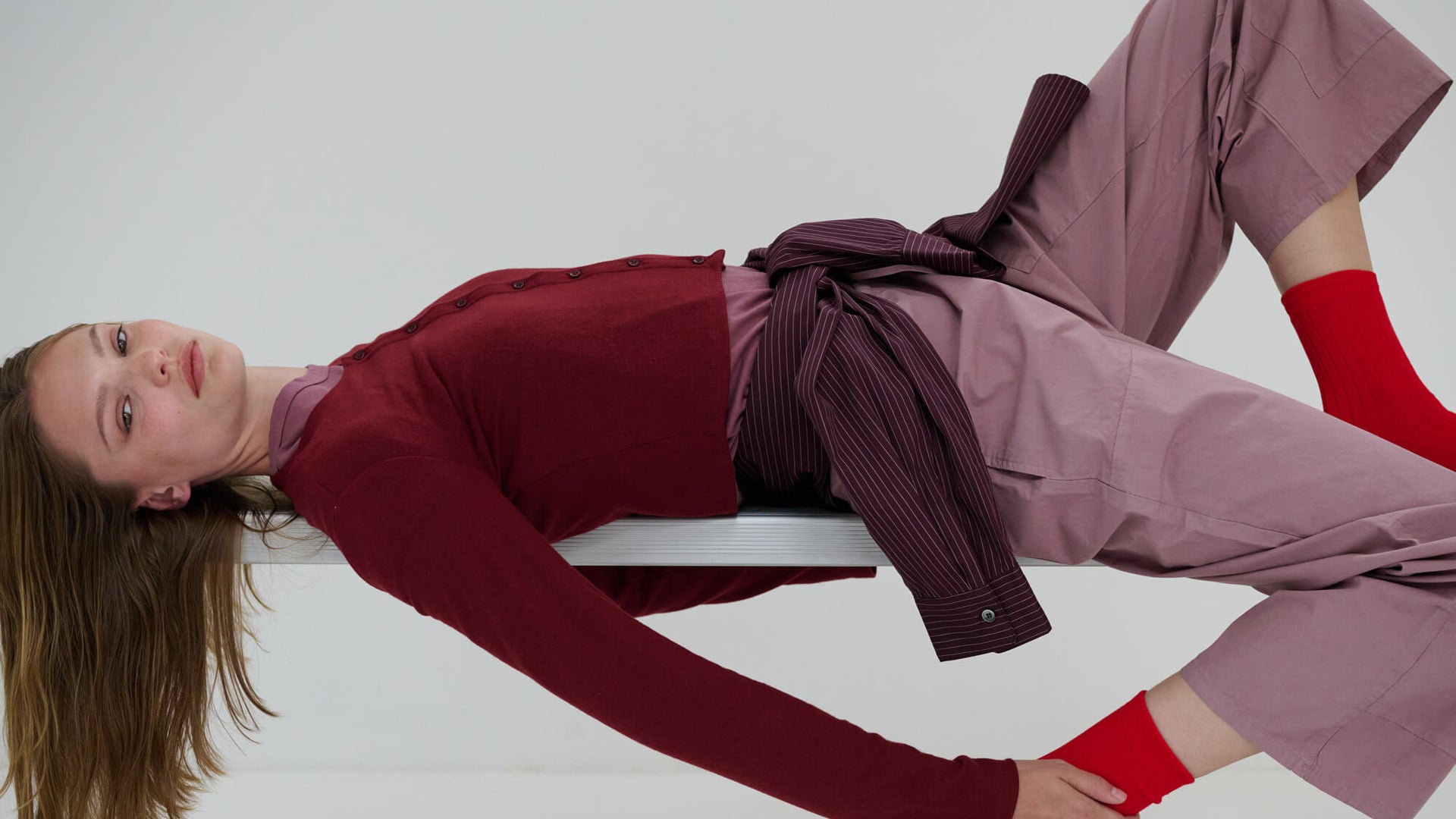 Women in pinot lauren sweater laying on bench, with Kyoto maud pants and button down