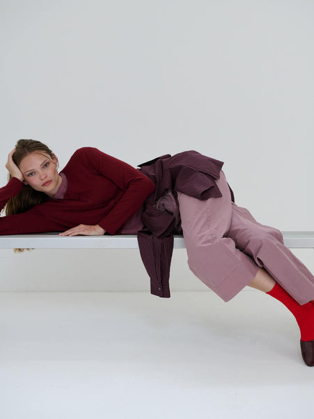 Women in pinot lauren sweater laying on bench, with Kyoto maud pants and button down