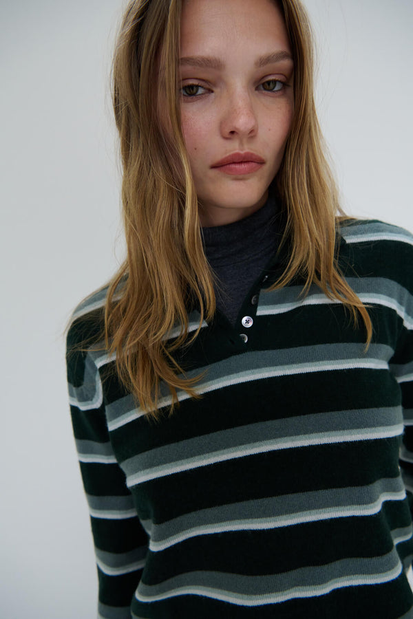 Close up of woman in James stripe polo layered over charcoal sweater.