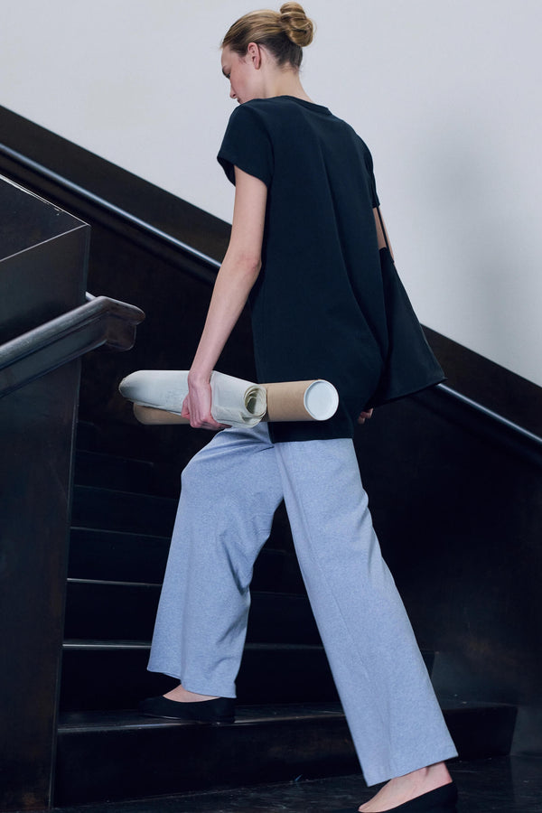 Walking up steps in blue lounge pant with dress layered over, holding paper.