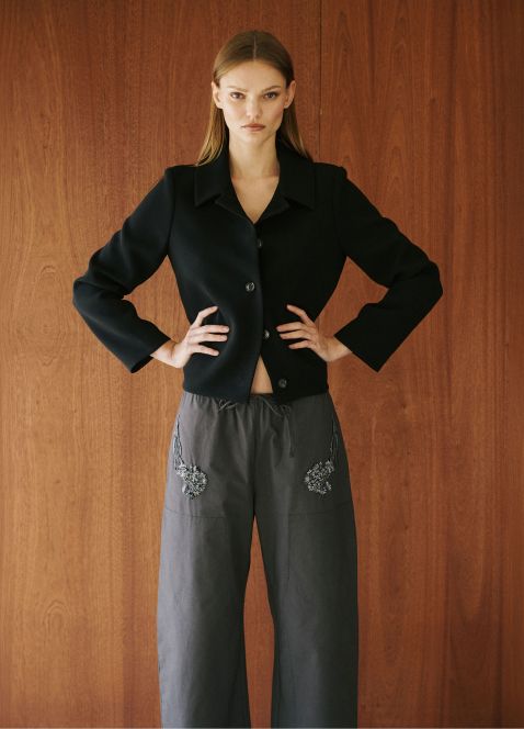 Model is standing with arms crossed wearing embroidered kyoto pants and black jacket.