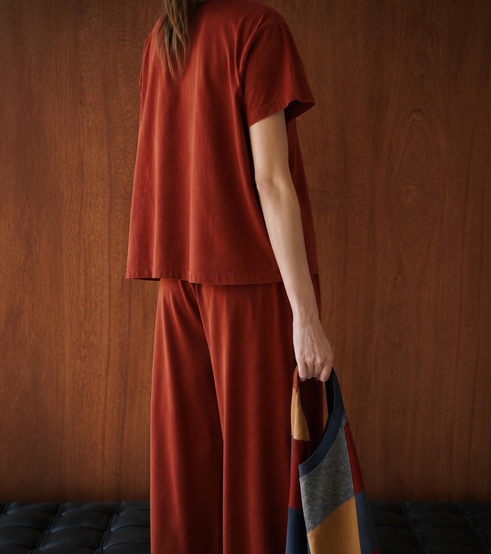 Back of woman wearing red matching tshirt and pants, holding argyle sweater