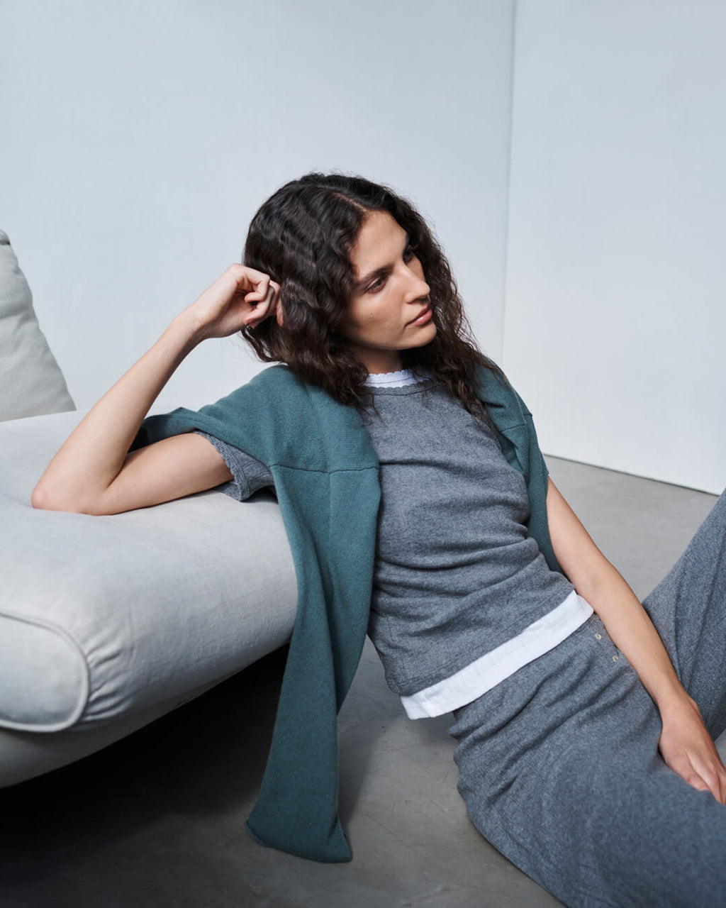 Woman leaning against chair, sitting on floor in Pointelle granite matching set with sweatshirt draped over