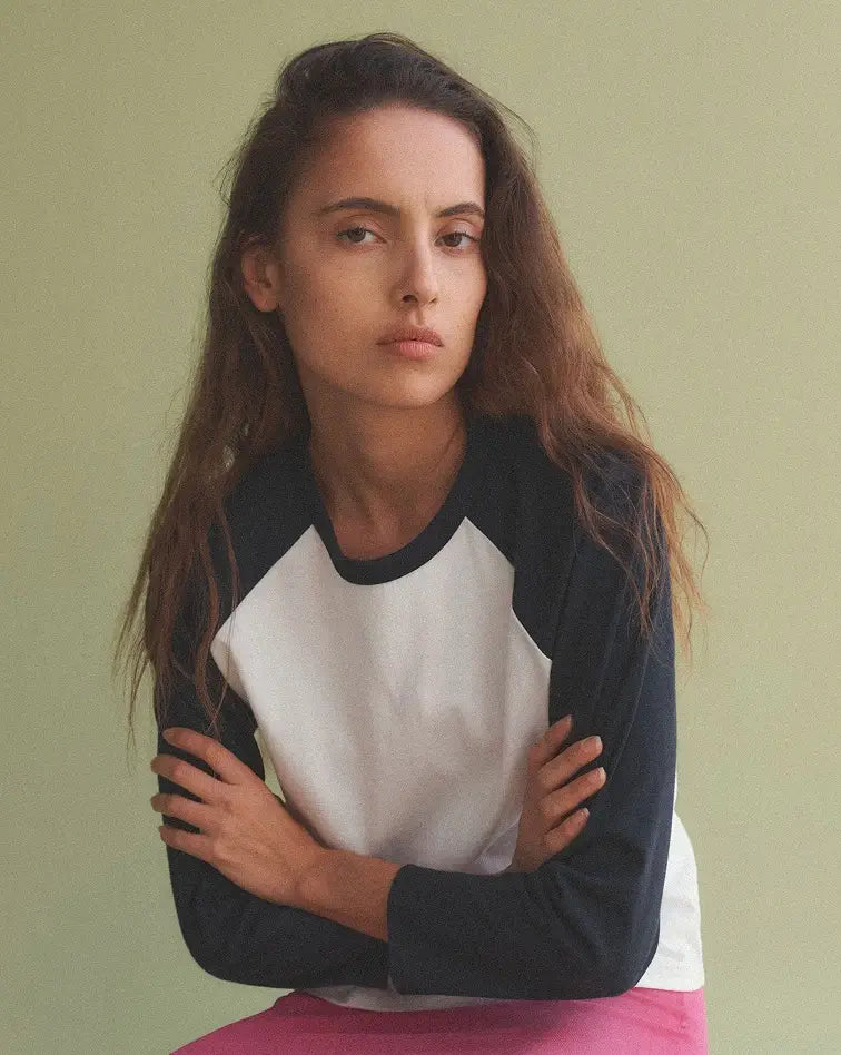Woman sitting in Margo Baseball tee with arms crossed.