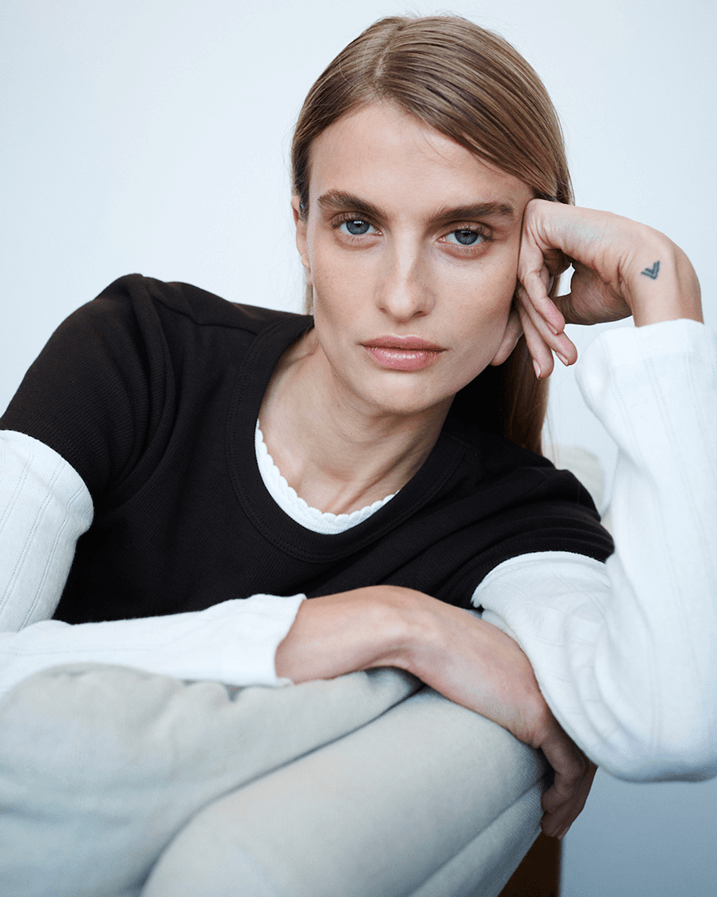 Woman leaning on hand in layered Pointelle long sleeve with chocolate colored tshirt.