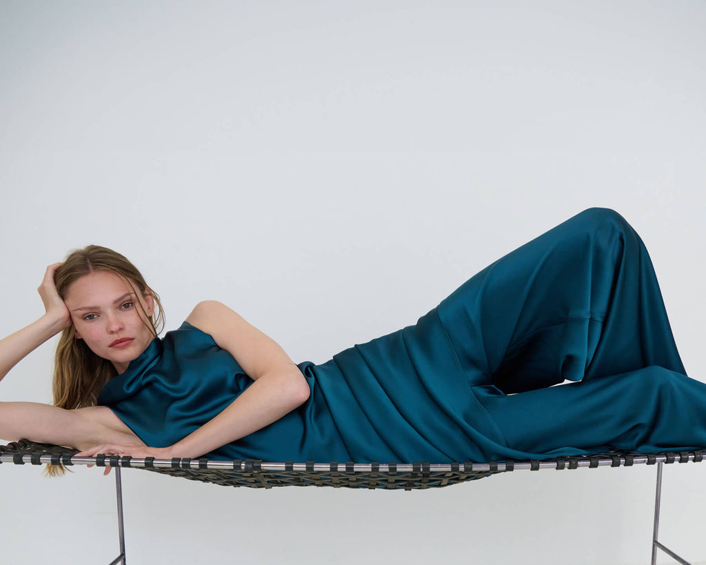 Woman laying down on her side on lounge, in Barb satin pacific matching set.