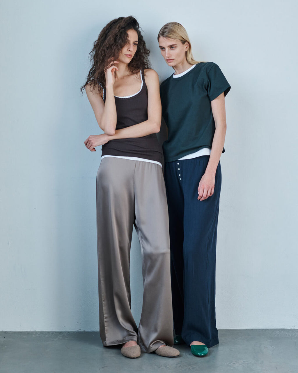 Woman leaning against wooden table in forest Kyoto pants and granite nando cardigan set.