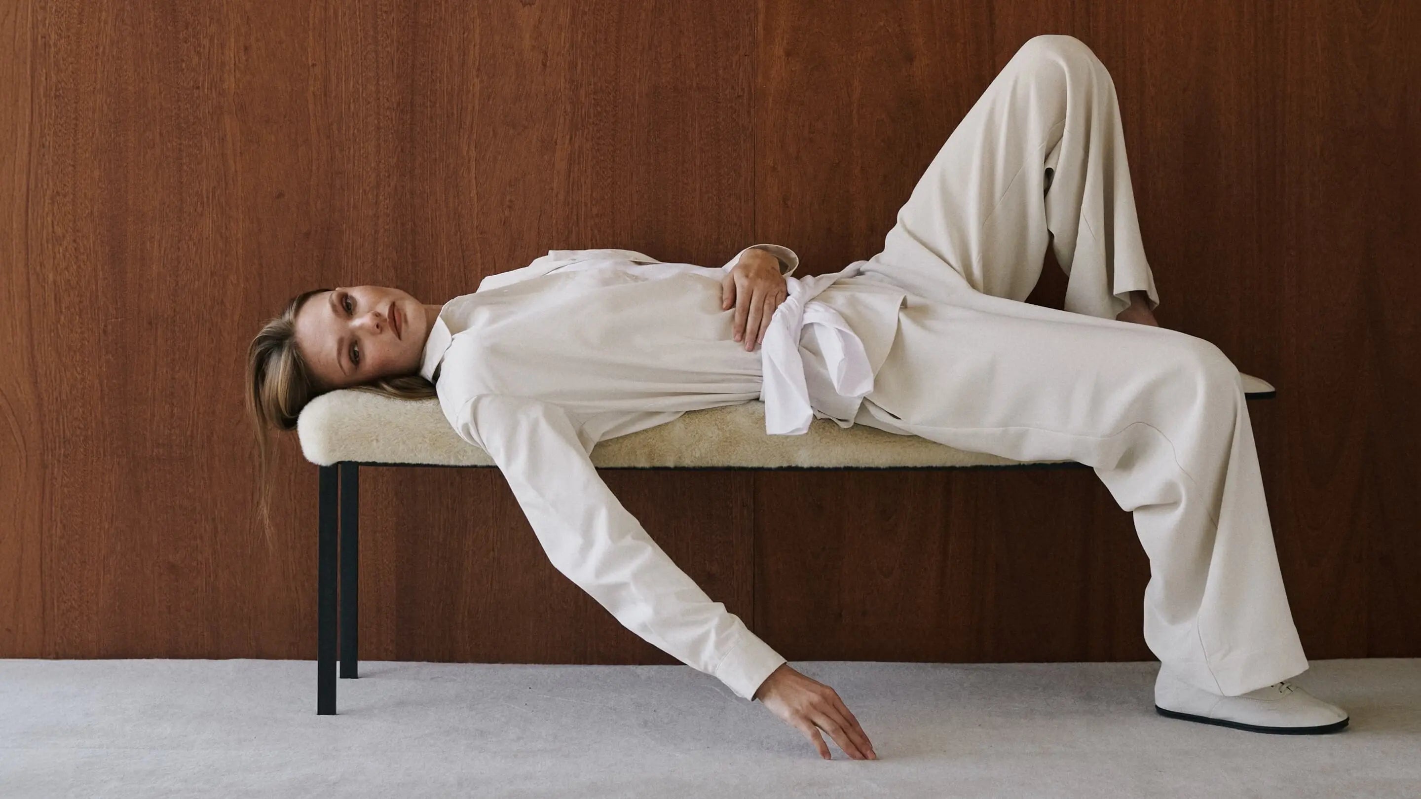 Model is laying down in white matching pants and top