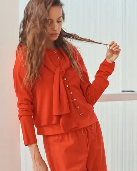 Woman standing with white background, in peach maxi dress.
