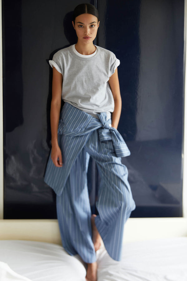 Woman standing on bed in layered grey and white Margos and Yoshi striped pants
