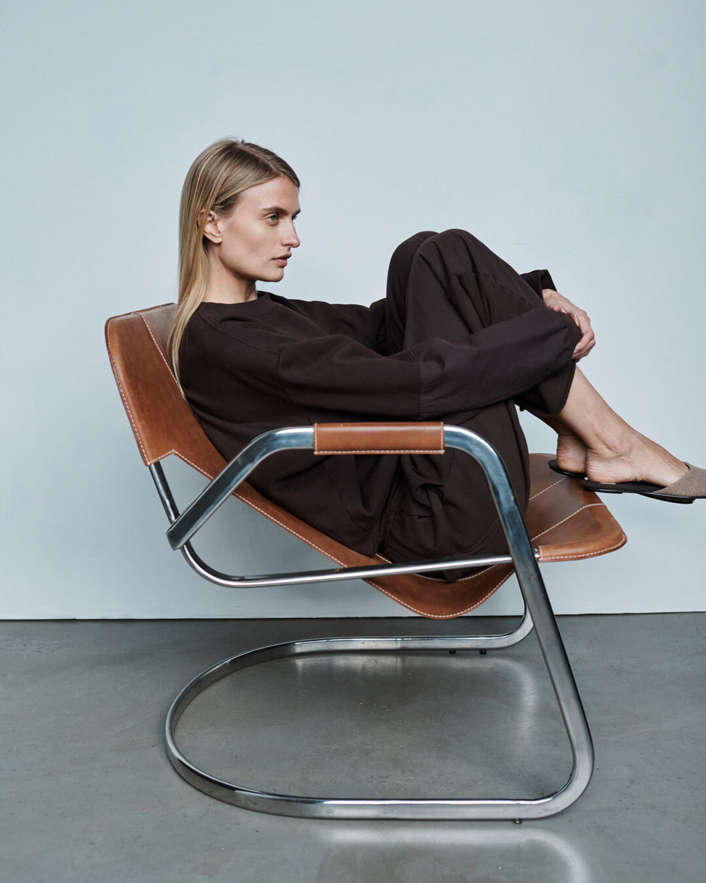 Woman leaning against wall in Bo trench with tights and ruby romy mules