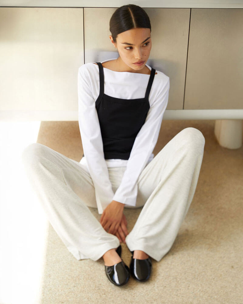 Woman sitting on steps with brown trousers, cardigan, turtleneck and zip up jacket