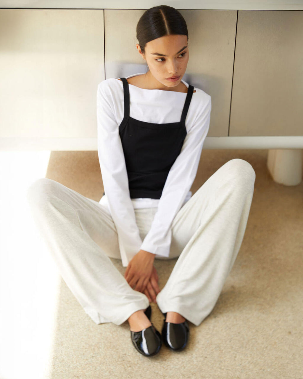 Woman sitting on steps with brown trousers, cardigan, turtleneck and zip up jacket