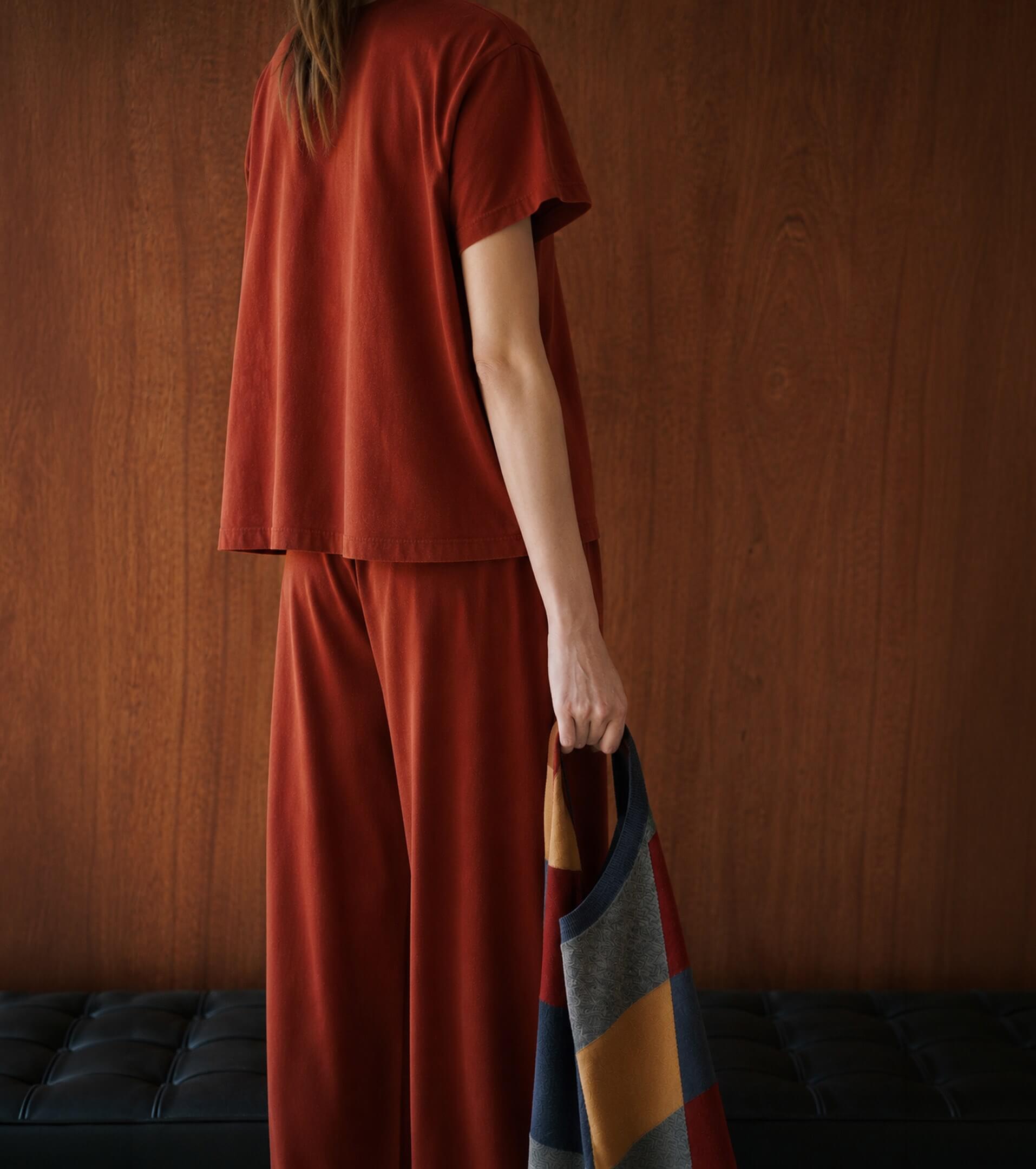 Back of woman wearing red matching tshirt and pants, holding argyle sweater