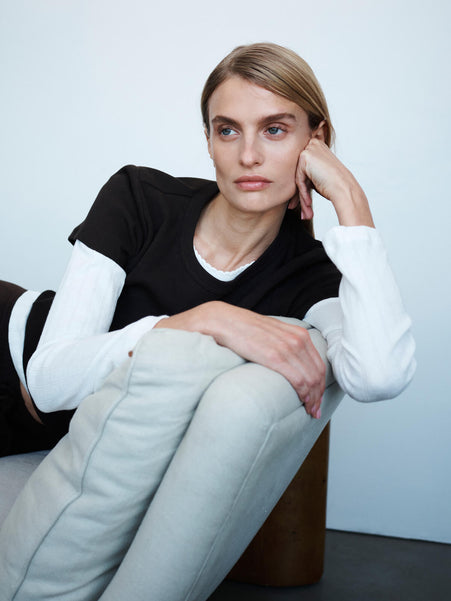 Woman leaning against chair on arm, in Pointelle layered underneath the classics in chocolate brown.