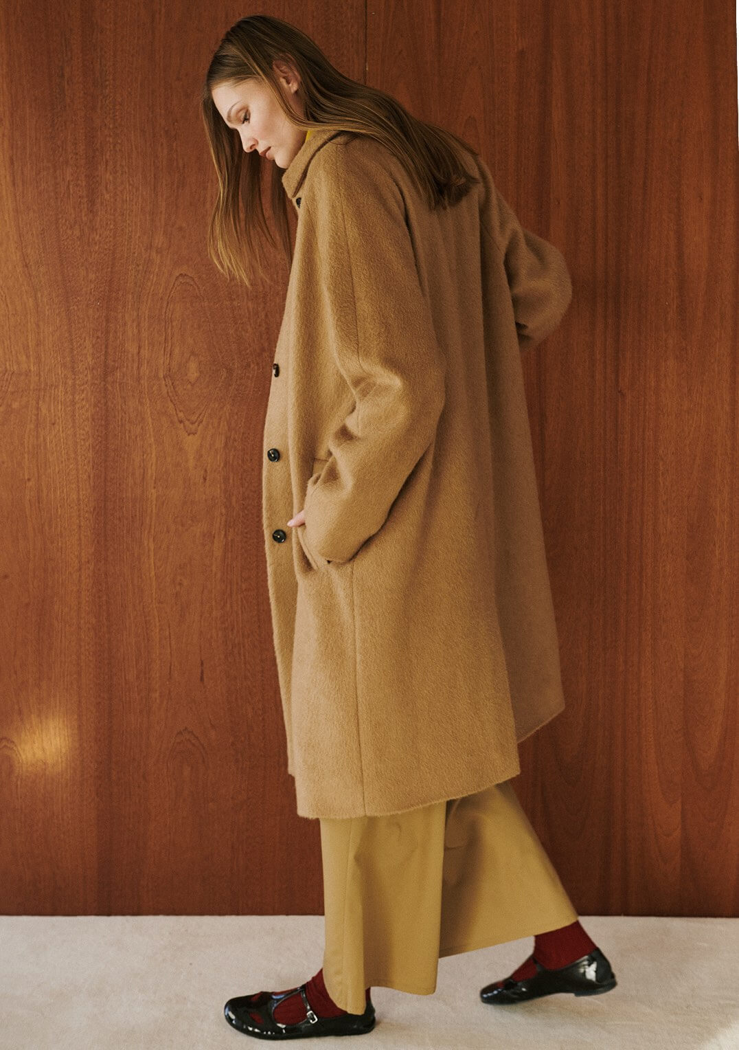 Woman walking in camel coat and pants.