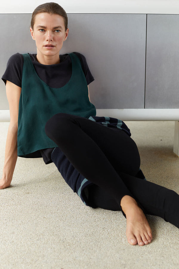 Woman sitting up posing wearing black leggings. Click to shop pants.