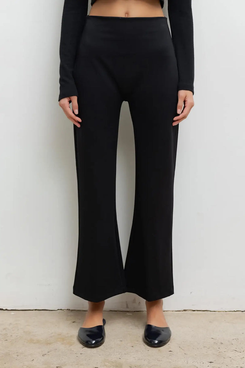 Close up of model wearing Rio high waist flare pants in black with patent black romy mules.