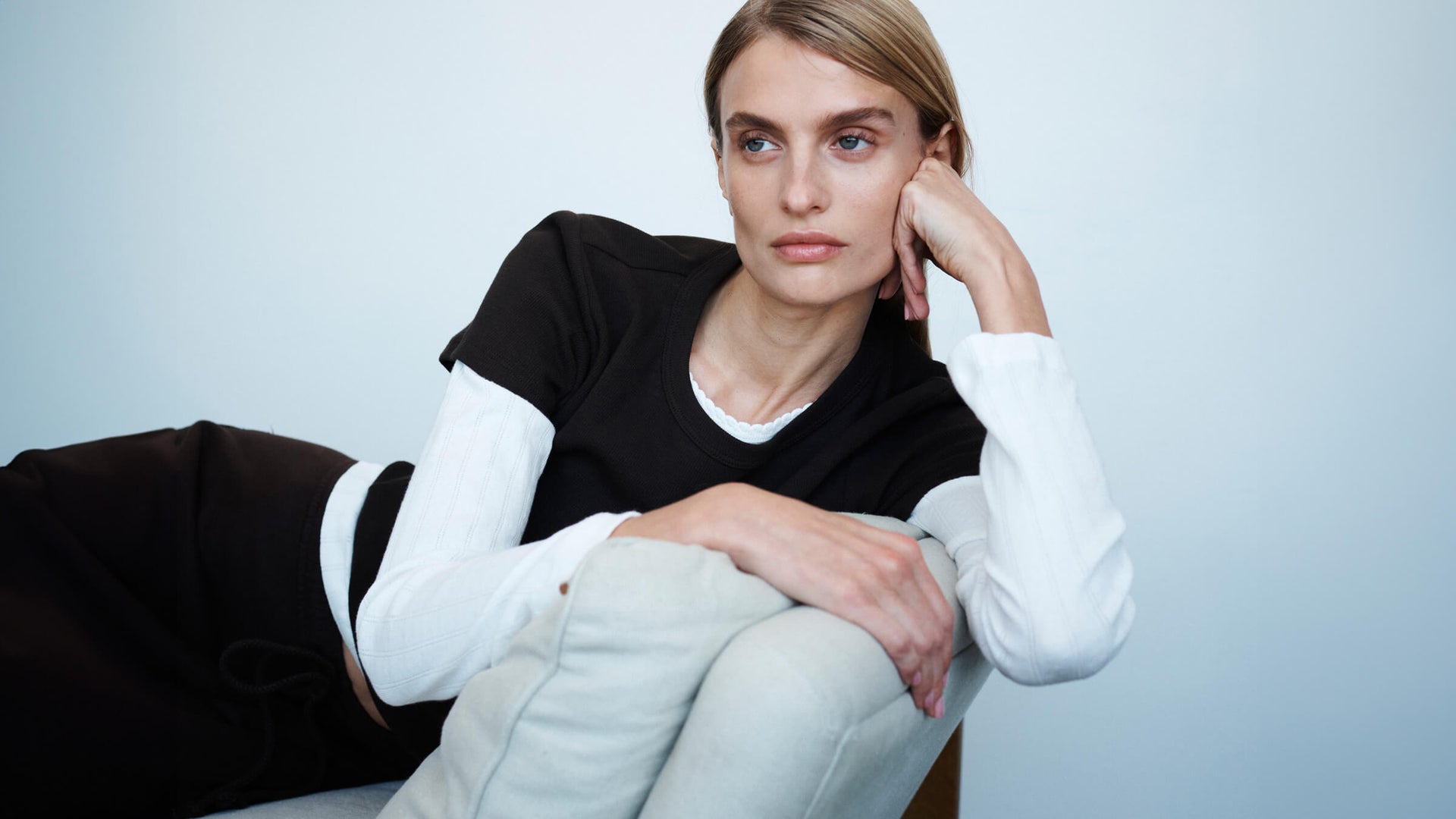 Woman leaning against chair on arm, in Pointelle layered underneath the classics in chocolate brown.