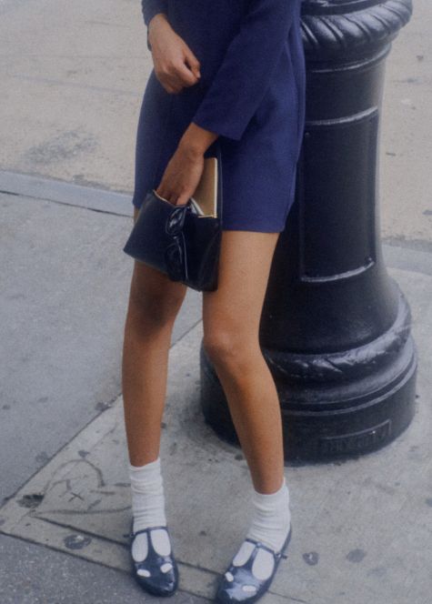 Bottom of model's outfit in blue dress and white socks with mary jane shoes on  sidewalk