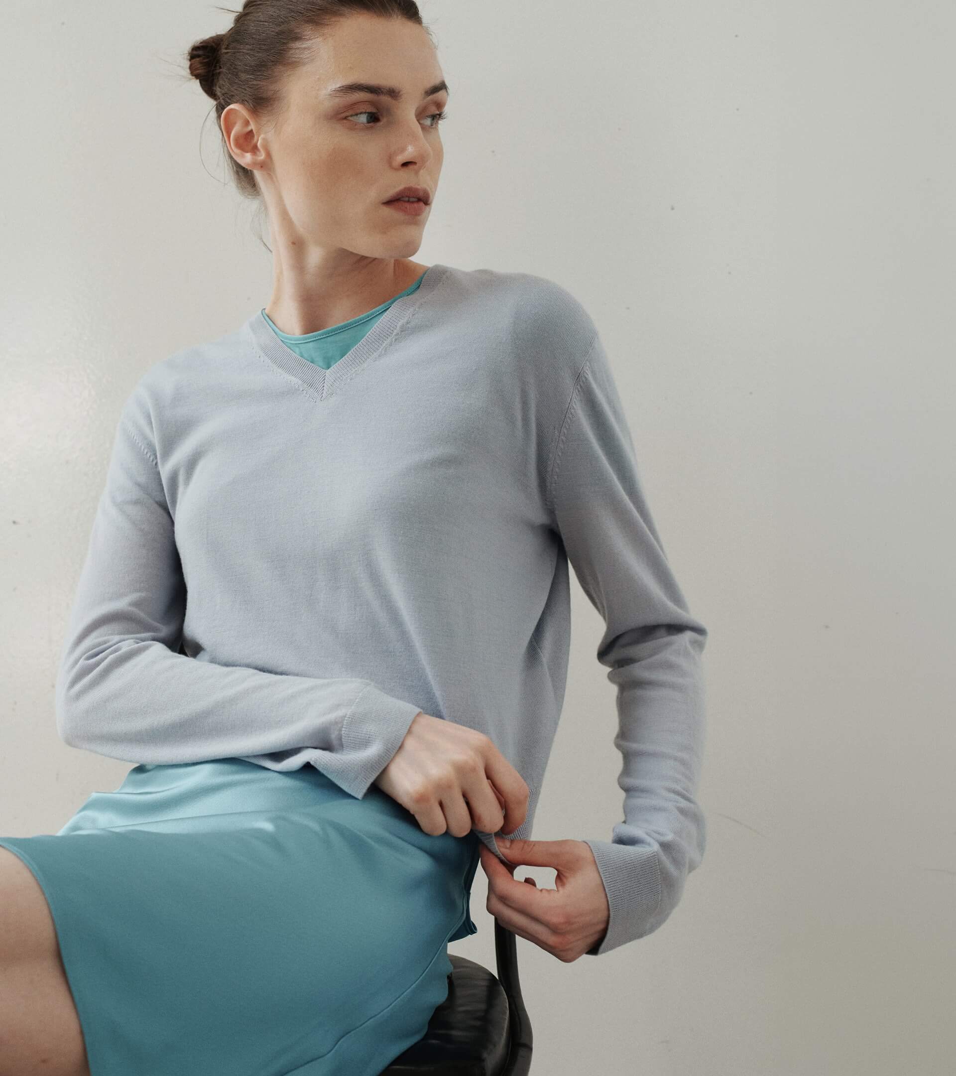 Close up of woman in blue satin skirt and v neck sweater