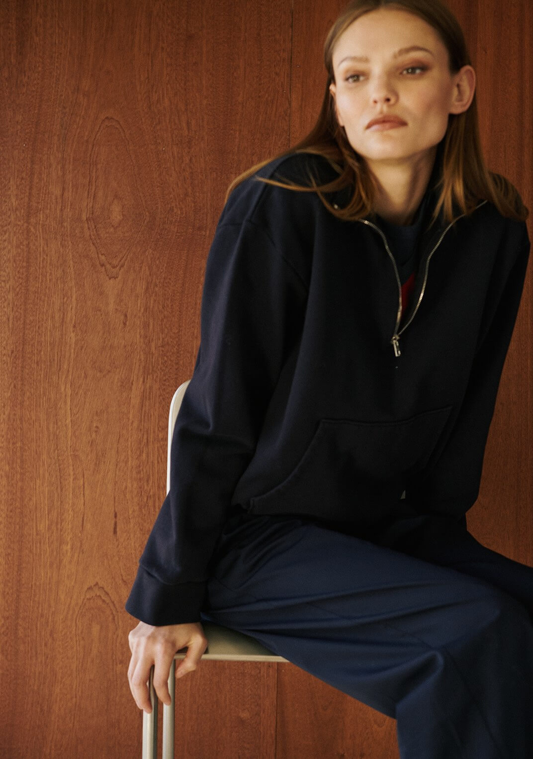 Close up of Anorak sweater in navy, woman sitting in chair.