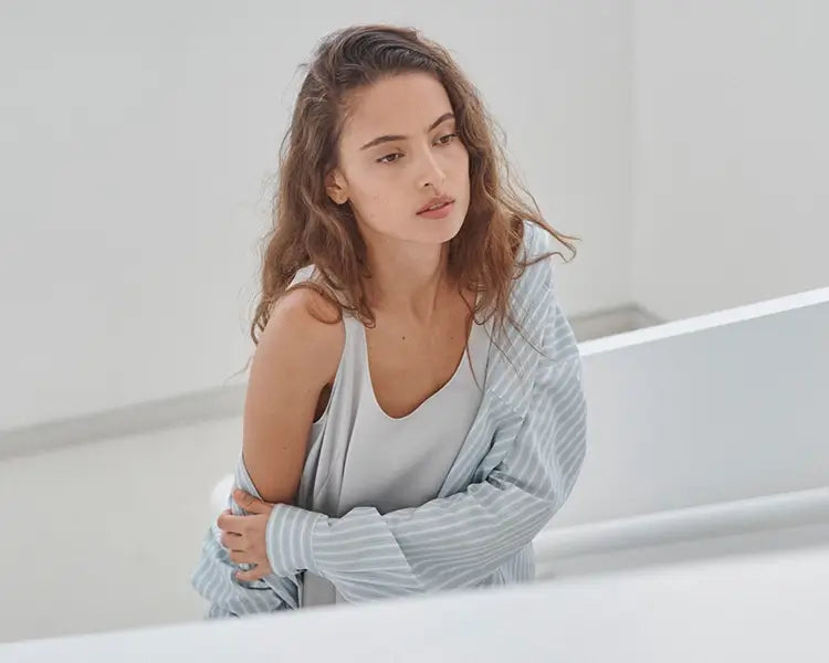 Woman leaned over in satin dress with striped button down.
