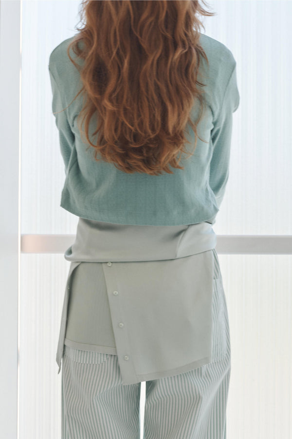 Back of woman standing in light green layers - striped pants, Pointelle cardigan and satin top.
