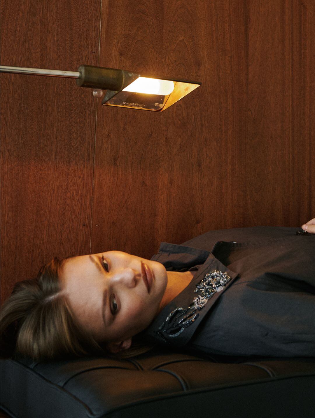 Model is laying down on couch in embroidered kyoto car coat in slate.