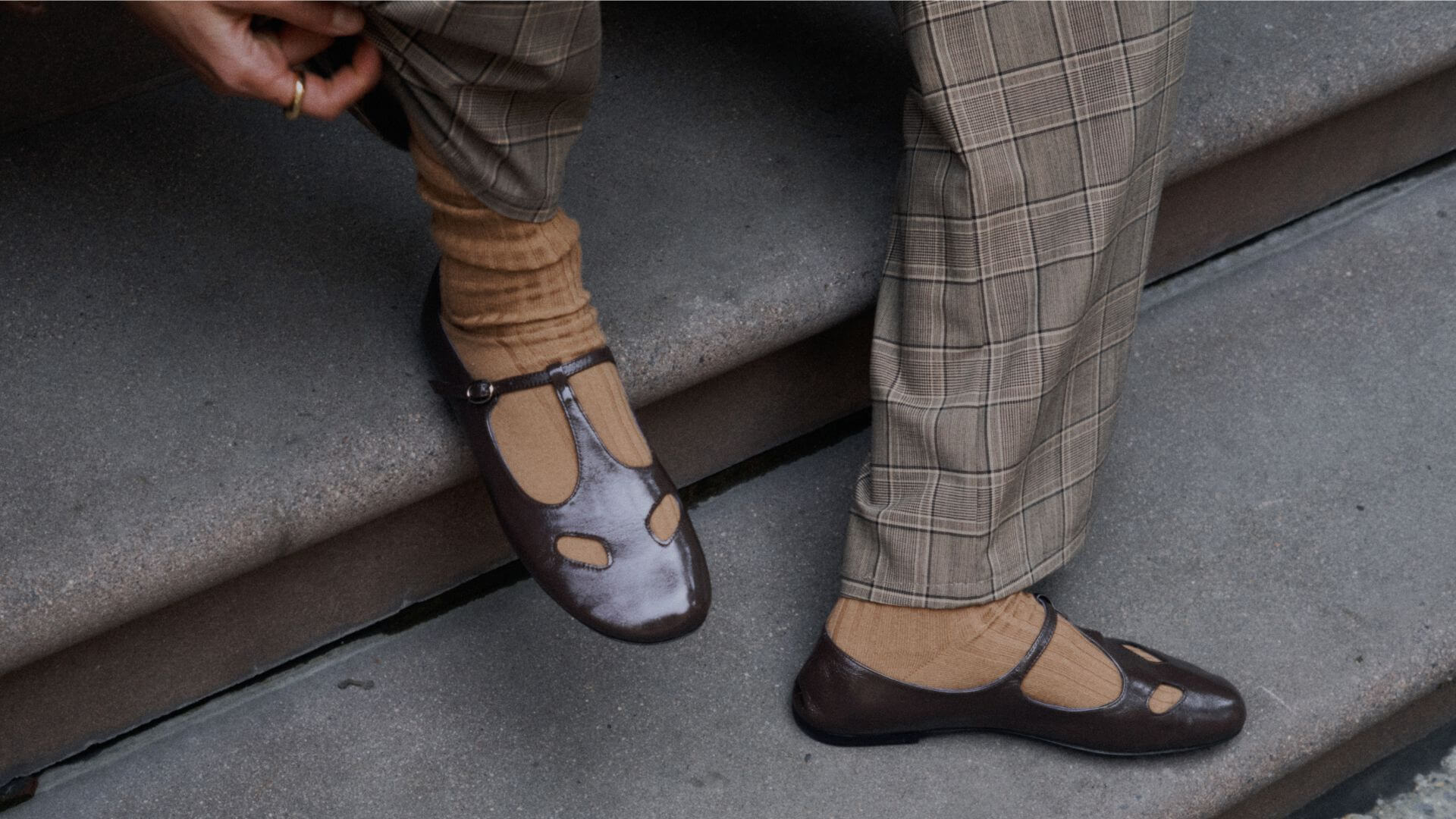 Close up of plaid pants and brown mary jane shoes on model on stairs.