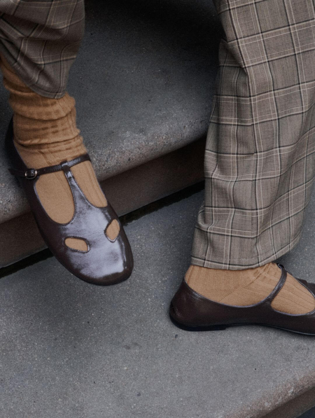 Close up of plaid pants and brown mary jane shoes on model on stairs.