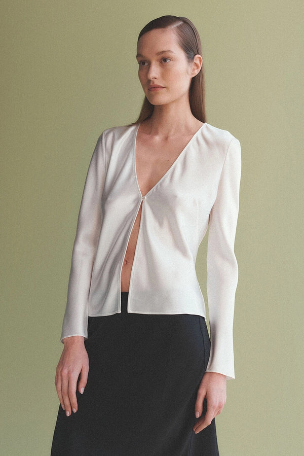 Woman standing in Barb white top, looking off into distance.