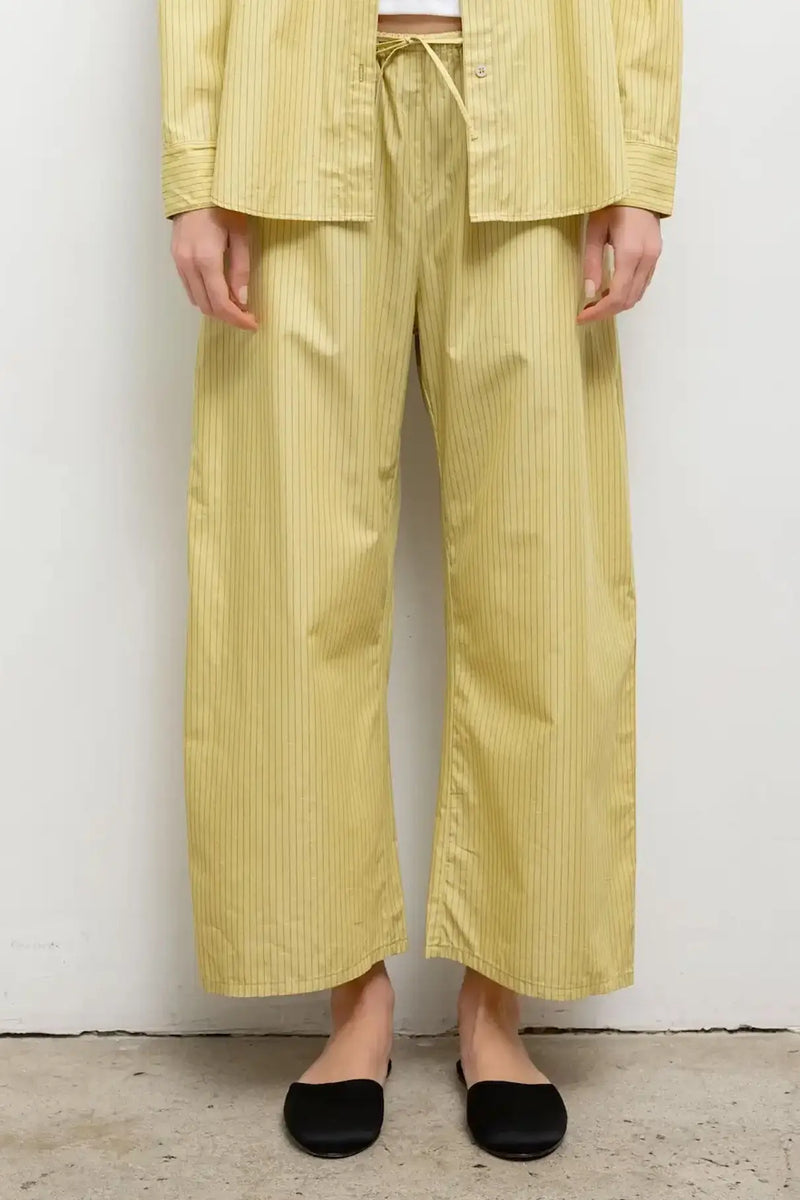 Close up of model wearing yellow yoshi stripe crop drawstring pant with black mules.
