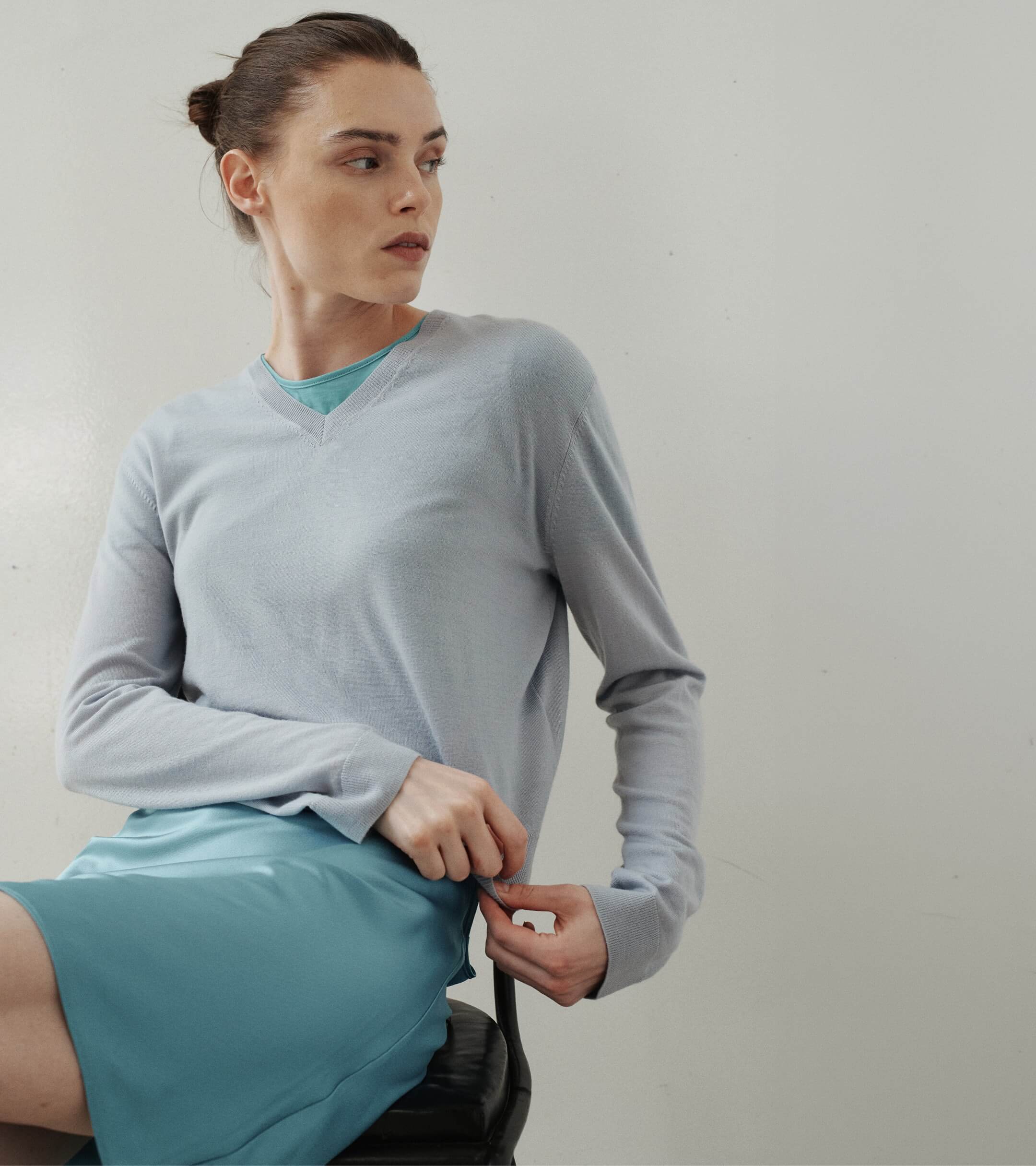 Close up of woman in blue satin skirt and v neck sweater